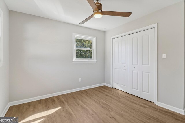 unfurnished bedroom featuring ceiling fan, a closet, and light hardwood / wood-style floors