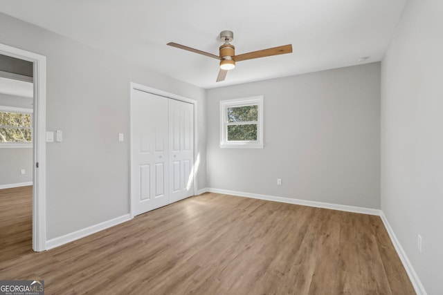 unfurnished bedroom featuring multiple windows, ceiling fan, a closet, and light hardwood / wood-style flooring