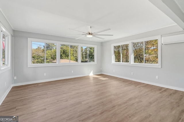 empty room with hardwood / wood-style flooring, ceiling fan, and a wall unit AC