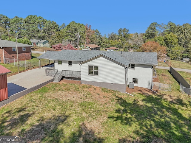 rear view of house featuring a deck, central AC unit, and a lawn