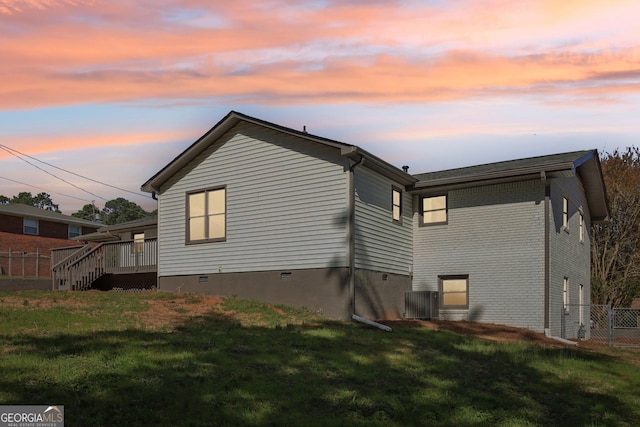 back house at dusk with a lawn and a wooden deck