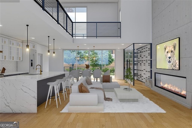 living room featuring a wealth of natural light, a fireplace, a high ceiling, and sink