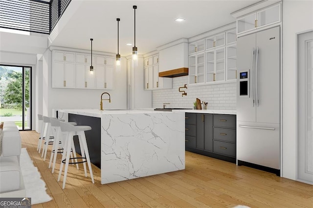 kitchen with a kitchen island with sink, white fridge with ice dispenser, and white cabinets