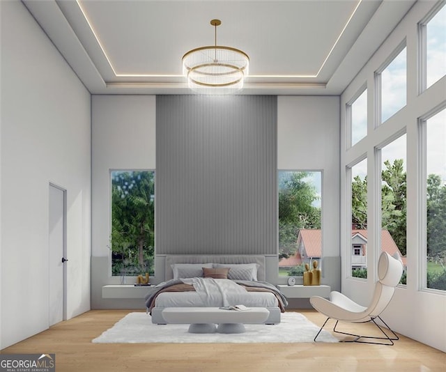 bedroom with a towering ceiling, light hardwood / wood-style floors, an inviting chandelier, and multiple windows