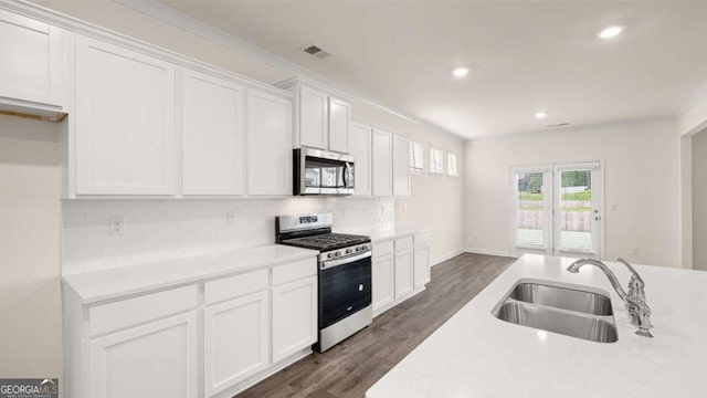 kitchen featuring white cabinets, sink, decorative backsplash, appliances with stainless steel finishes, and dark hardwood / wood-style flooring