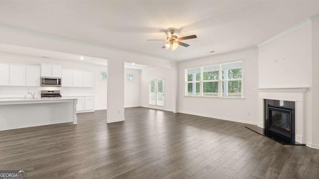 unfurnished living room featuring dark hardwood / wood-style flooring, ceiling fan, crown molding, and sink