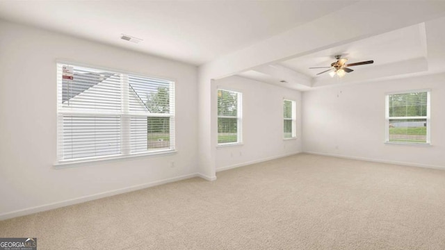 spare room with ceiling fan, light colored carpet, and a tray ceiling