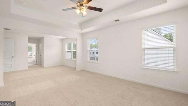 carpeted empty room with ceiling fan and a tray ceiling