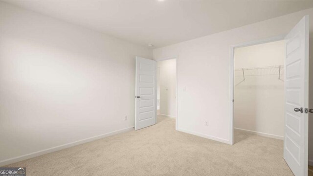 unfurnished bedroom featuring a walk in closet, light carpet, and a closet