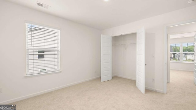 unfurnished bedroom with light carpet and a closet