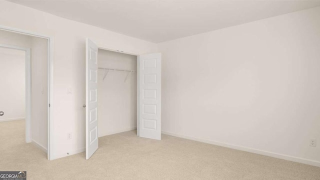 unfurnished bedroom with light carpet and a closet