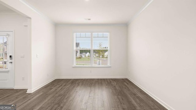 spare room featuring a healthy amount of sunlight, dark hardwood / wood-style floors, and ornamental molding