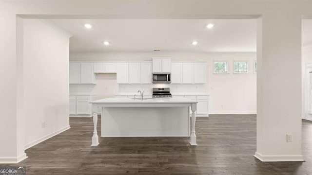 kitchen featuring white cabinetry, sink, stove, a breakfast bar area, and a center island with sink