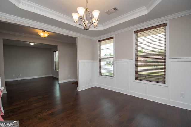 unfurnished room with a tray ceiling, dark wood-type flooring, a notable chandelier, and ornamental molding