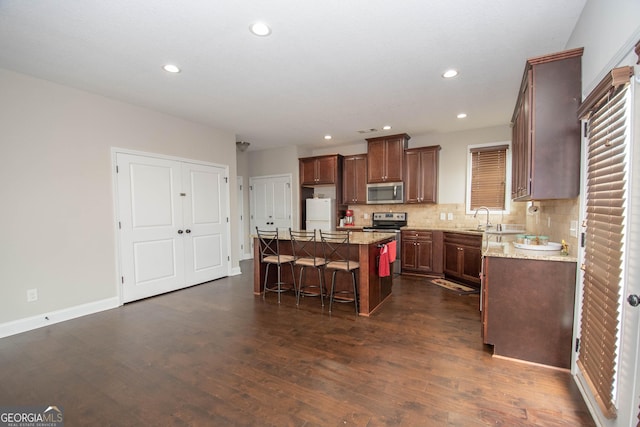 kitchen with sink, a center island, a kitchen breakfast bar, tasteful backsplash, and appliances with stainless steel finishes