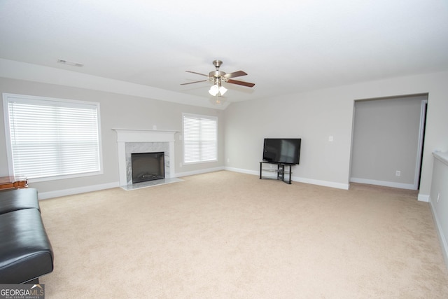 unfurnished living room with light carpet, vaulted ceiling, ceiling fan, and a premium fireplace