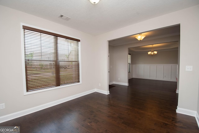 unfurnished room with a chandelier, dark wood-type flooring, and a textured ceiling