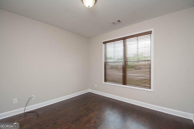 empty room featuring dark wood-type flooring and a textured ceiling