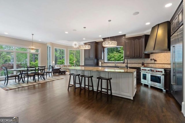 kitchen with custom exhaust hood, a center island, high end appliances, decorative backsplash, and light stone countertops