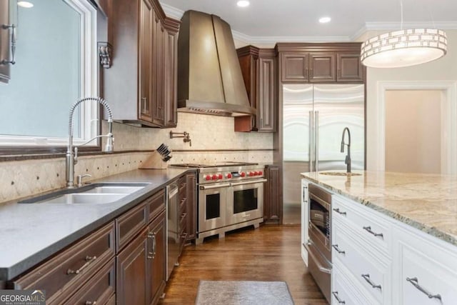 kitchen featuring white cabinetry, sink, wall chimney exhaust hood, tasteful backsplash, and built in appliances