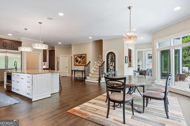 dining space with sink, ornamental molding, dark wood-type flooring, and an inviting chandelier