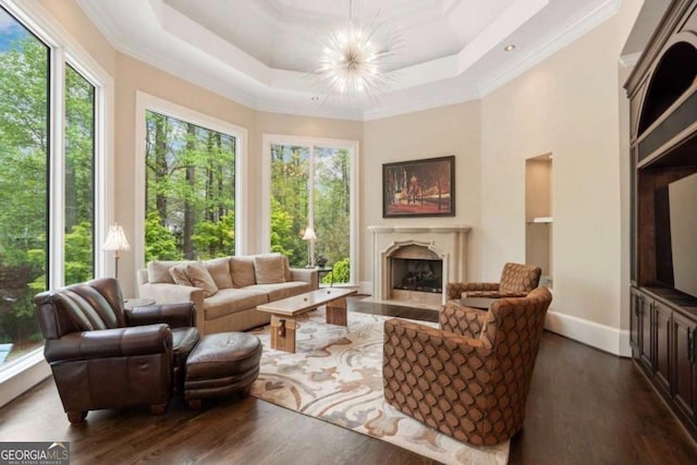 living room with a raised ceiling, a fireplace, a chandelier, and dark hardwood / wood-style floors