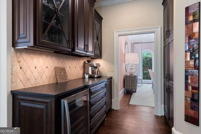 bar featuring dark wood-type flooring, backsplash, ornamental molding, dark brown cabinetry, and beverage cooler