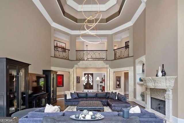 living room featuring a high end fireplace, built in shelves, crown molding, and a high ceiling