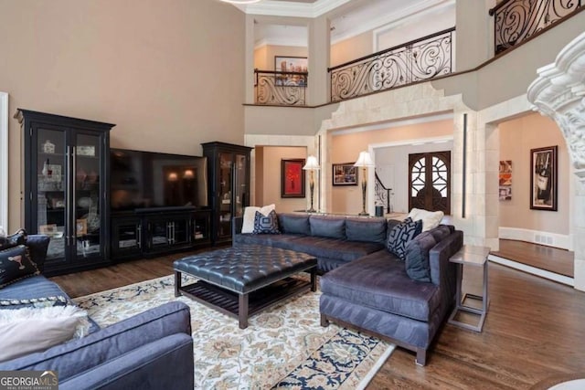 living room with ornamental molding, dark wood-type flooring, a high ceiling, and french doors