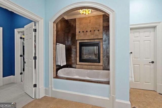 bathroom with tile patterned floors, ornamental molding, a bath, and a tiled fireplace