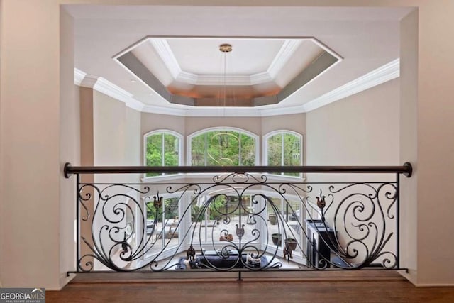 staircase with a raised ceiling, hardwood / wood-style flooring, and ornamental molding