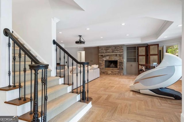 interior space featuring crown molding, parquet floors, a fireplace, and a tray ceiling