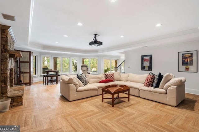 living room with a fireplace, light parquet flooring, a tray ceiling, and crown molding