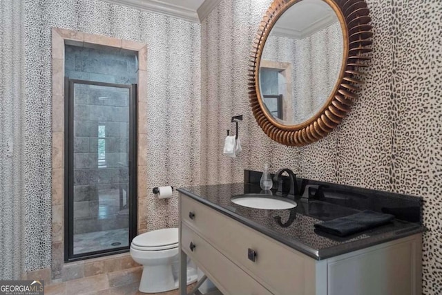 bathroom with vanity, toilet, a shower with door, and crown molding