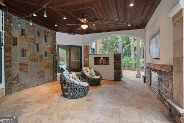 view of patio with an outdoor living space with a fireplace and ceiling fan