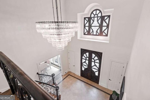 foyer entrance with a chandelier, french doors, and a towering ceiling