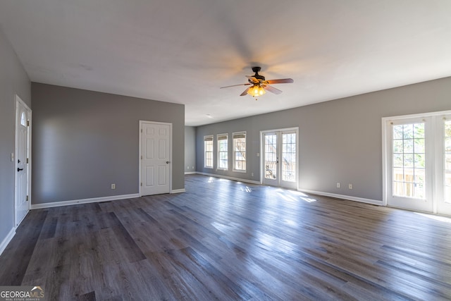 unfurnished living room featuring ceiling fan, a healthy amount of sunlight, dark hardwood / wood-style flooring, and french doors