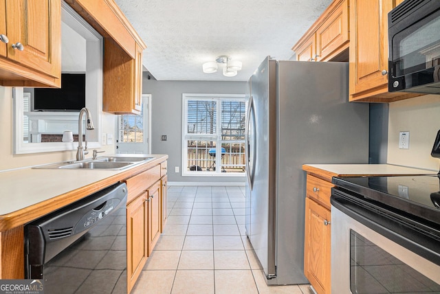 kitchen with black appliances, sink, light tile patterned floors, and a textured ceiling