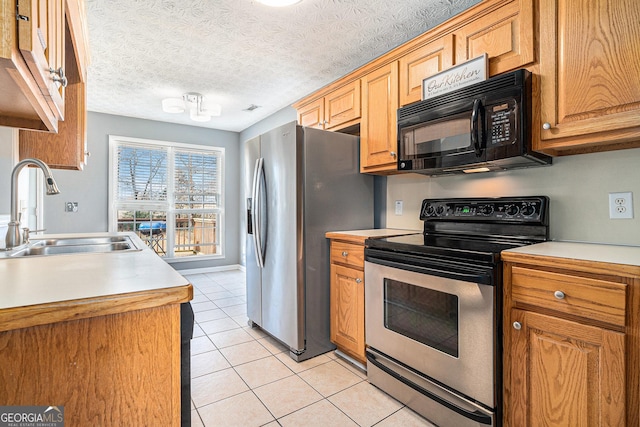 kitchen featuring a textured ceiling, light tile patterned flooring, sink, and appliances with stainless steel finishes