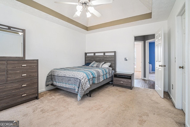 carpeted bedroom featuring a textured ceiling, a tray ceiling, and ceiling fan