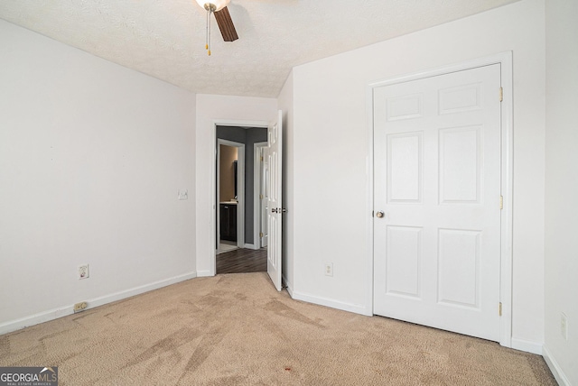 unfurnished bedroom featuring a textured ceiling, light colored carpet, and ceiling fan