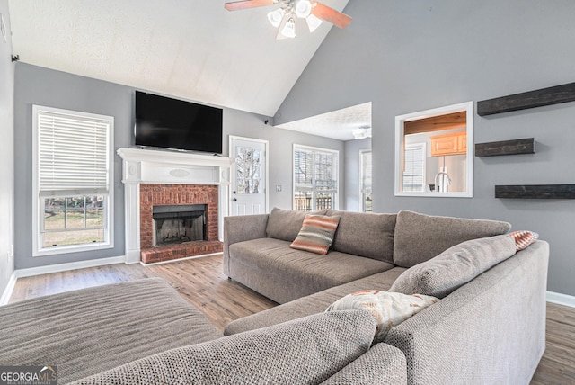 living room with light hardwood / wood-style flooring, a brick fireplace, a wealth of natural light, and ceiling fan