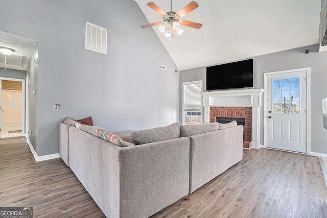 living room featuring ceiling fan, a fireplace, high vaulted ceiling, and hardwood / wood-style floors