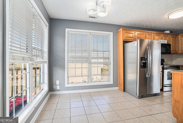 kitchen with light tile patterned flooring, a textured ceiling, and appliances with stainless steel finishes