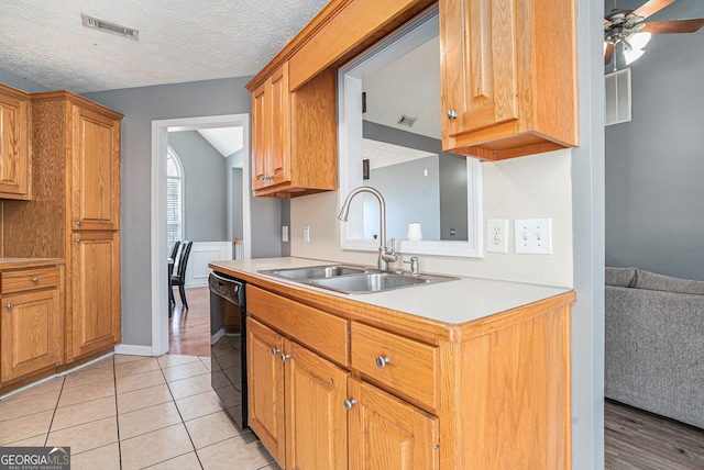 kitchen featuring a textured ceiling, ceiling fan, sink, light tile patterned floors, and dishwasher