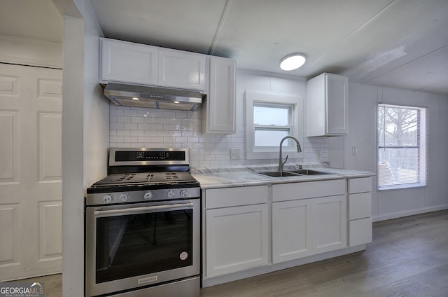 kitchen with stainless steel gas stove, white cabinets, range hood, and sink