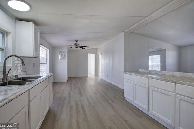 kitchen featuring light wood-type flooring, ceiling fan, sink, white cabinetry, and lofted ceiling