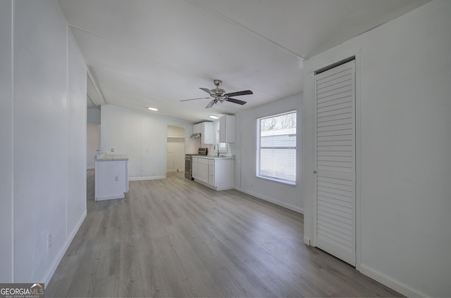 unfurnished living room with light wood-type flooring, ceiling fan, and sink