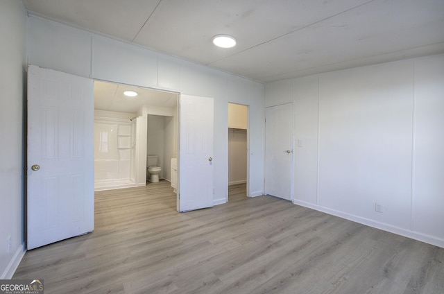 unfurnished bedroom featuring connected bathroom, a closet, and light hardwood / wood-style flooring