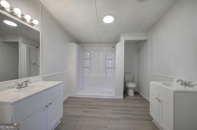 bathroom featuring a shower, hardwood / wood-style floors, vanity, and toilet